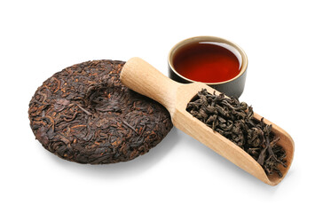 Scoop of dry puer tea and cup on white background
