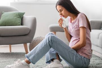 Young pregnant woman with nosebleed and tissue at home