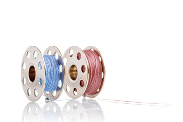 spools of blue and pink thread on a white background