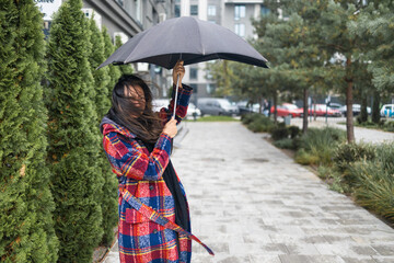 Woman trying to hold her umbrella in strong wind