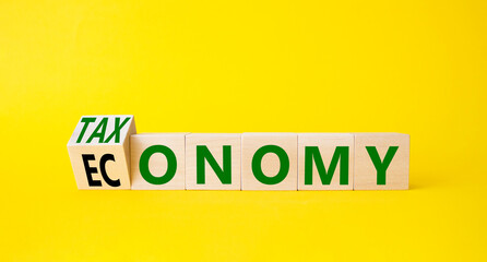 Taxonomy and economy symbol. Turned cubes with words Economy and Taxonomy. Beautiful yellow background. Business and Taxonomy and economy concept. Copy space