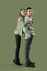 Fashionable young couple in autumn clothes on green background