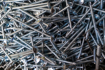 A lot of metal screws close-up in bulk.