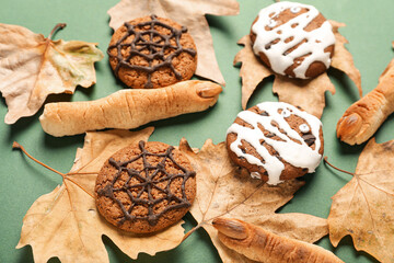 Tasty Halloween cookies with fallen leaves on green background