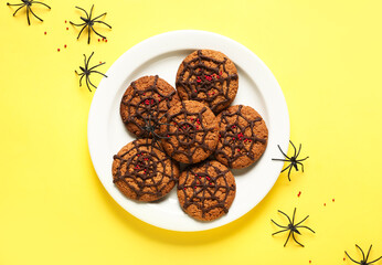 Obraz na płótnie Canvas Plate with Halloween spiderweb cookies and spiders on yellow background