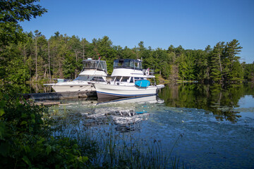 Two boats moored to a dock at the top of Jones Falls Lock 39 on the Rideau Canal in Ontario, Canada