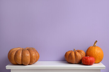 Halloween pumpkins on mantelpiece near violet wall