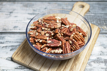roasted walnuts in a glass bowl on a chopping board on table 