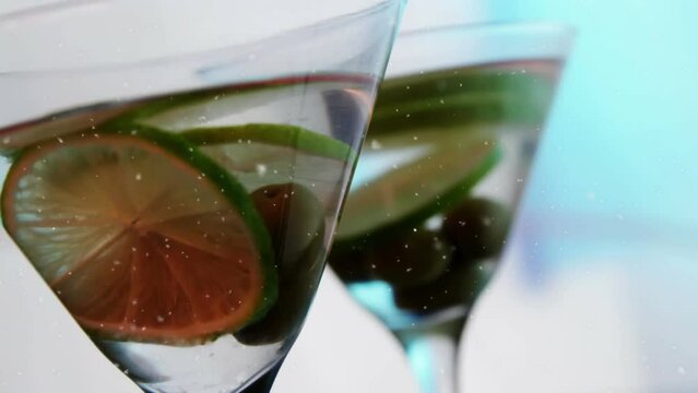 Animation of snow falling over drink with olives and lime