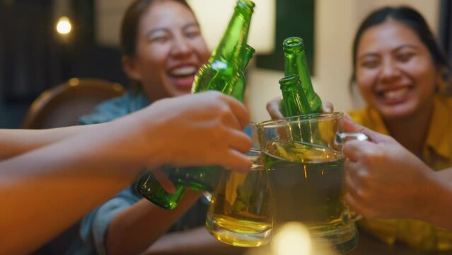 Closeup of Group of multiethnic adult Asia friend drinking alcohol beer bottle glass and having fun laugh enjoy hangout party in night life indoor home. Happy hour millennial generation inside house.