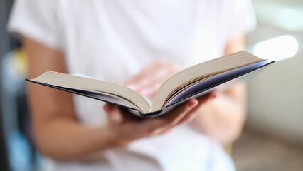 Woman is reading book and leafing through pages closeup