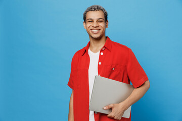 Young fun happy IT man of African American ethnicity 20s wear red shirt hold use work on laptop pc...