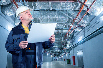 Man engineer. Engineering Communication. Engineer stands under ventilation pipes. Ventilation...