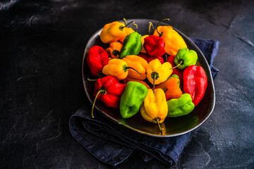 Overhead view of a bowl of assorted red, yellow and green, chilli peppers