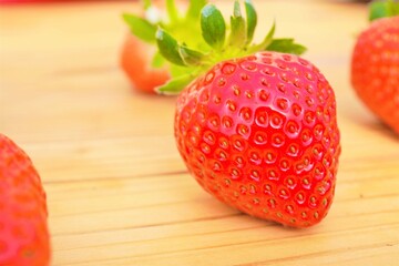 木目のある机の上に置かれた美味しそうなイチゴのクローズアップ

