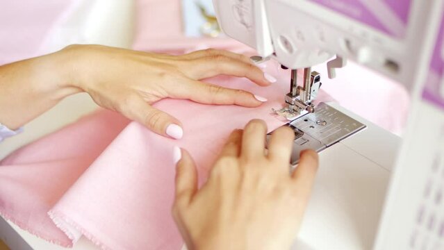 Woman clothing designer sews fabrics on a sewing machine. Needlework and handmade hobby.