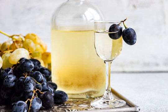 Glass of Georgian chacha on a metal tray with black and green grapes