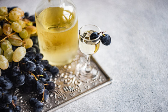 Glass of Georgian chacha on a metal tray with black and green grapes
