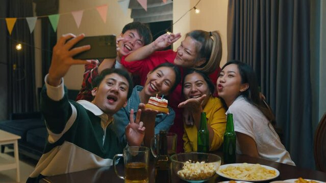Group of young adult Asia friend with birthday cake look at camera shooting video photo on mobile app fun hangout party in night life indoor home. Happy hour time millennial generation inside house.