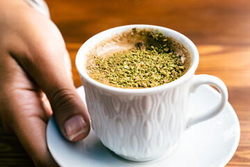 Pistachio coffee in a white cup. Woman with coffee in hand. Turkish coffee with pistachio.