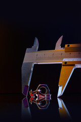 metal, chrome-plated nuts of different sizes and a caliper measuring the nut. Black background