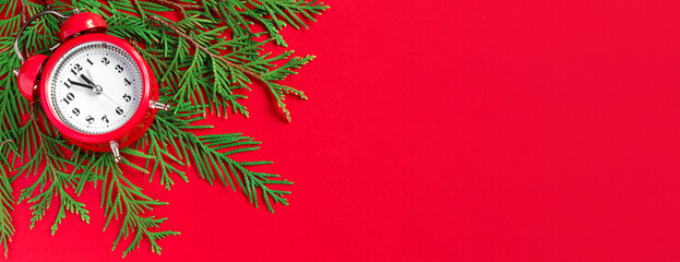 Alarm clock  with tree branches on red paper background. 5 minutes before the New Year. Creative...