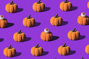 Pumpkins and eyeballs, creative arrangement on purple background. Halloween celebration inspired.