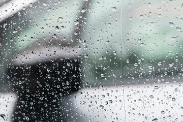Raindrops on the glass window with outline of a car