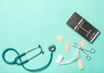 Stethoscope, surgical scissors, medical plasters and gauze roll on color background