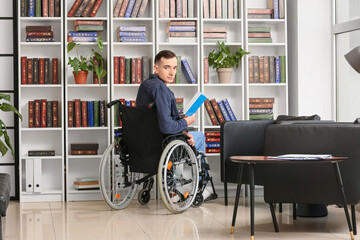 Young man in wheelchair choosing book in home library