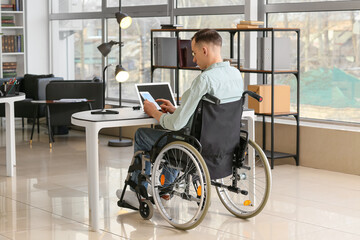 Fototapeta na wymiar Young man in wheelchair working in office
