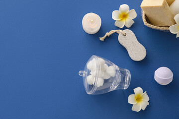 Bath accessories, cosmetics and tropical flowers on blue background