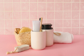 Bath accessories on table near pink tile wall