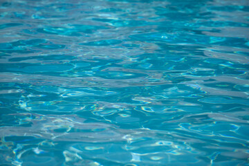 Fototapeta na wymiar Background of blue water in swimming pool with sun reflection, ripple water wave in pool. Clear water background.