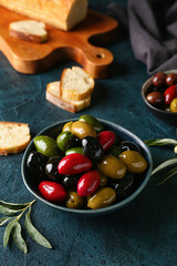 Bowl of different delicious olives on dark color background