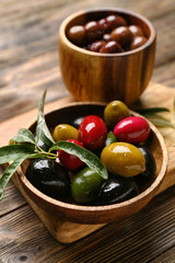 Plate with different kinds of tasty olives on wooden table, closeup