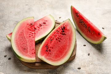 Cutting board with slices of watermelon on grunge background