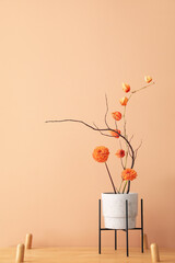 Pot with beautiful ikebana on shelf near beige wall