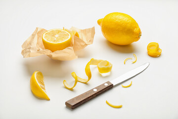 Ripe lemons, peel and knife on white background