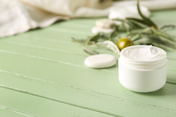 Fototapeta na wymiar Jar of olive cream on color wooden background
