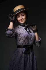 A girl in a blue retro dress in the style of the 1900s. A woman adjusts her hat in lace gloves....