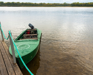 Obraz premium a parked metal boat with an outboard motor to a wooden pier.