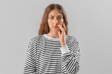 Young woman with nosebleed on light background
