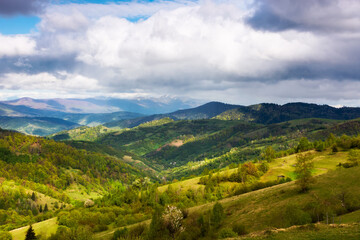 green carpathian landscape in spring time. beautiful mountain landscape with rural valley and village in the distance. clouds on the sky above the borzhava ridge