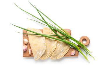 Board with raw chebureks, garlic and green onion on white background