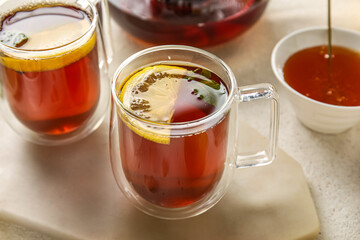 Board with glass cup of black tea and lemon on white table, closeup