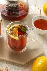 Board with glass cup of black tea and lemon on white table, closeup
