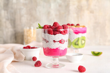 Glass with tasty chia seed pudding and raspberry on table