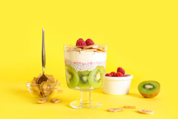 Glass of tasty chia seed pudding with fruits on yellow background