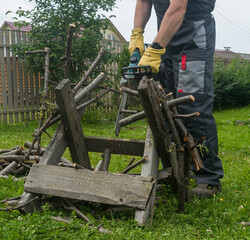 a man saws an old tree for firewood with an electric chain saw.